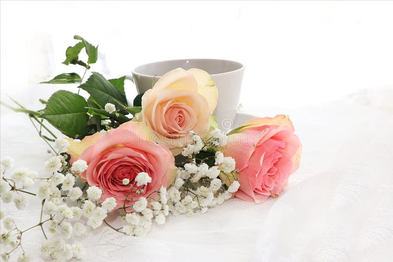 Ένα φλιτζάνι του καφέ και λουλούδια σε ένα ελαφρύ υπόβαθρο
